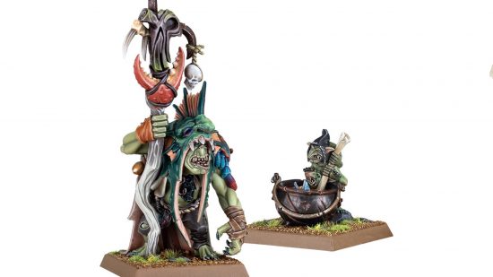 Warhammer the Old World Orcs and Goblins shaman wearing the scalp of a troll as a head, accompanied by a pot-stirring goblin
