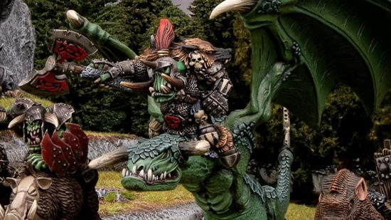Warhammer the Old World Orcs and Goblins - an armored Orc Warboss riding a lumpen Wyvern, a winged, draconic creature with large fangs and green scales