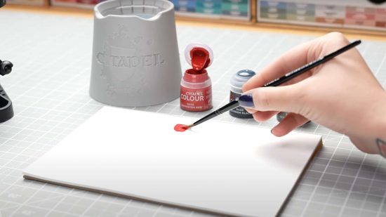 Closeup shot of someone's hand as they use Warhammer painting accessories