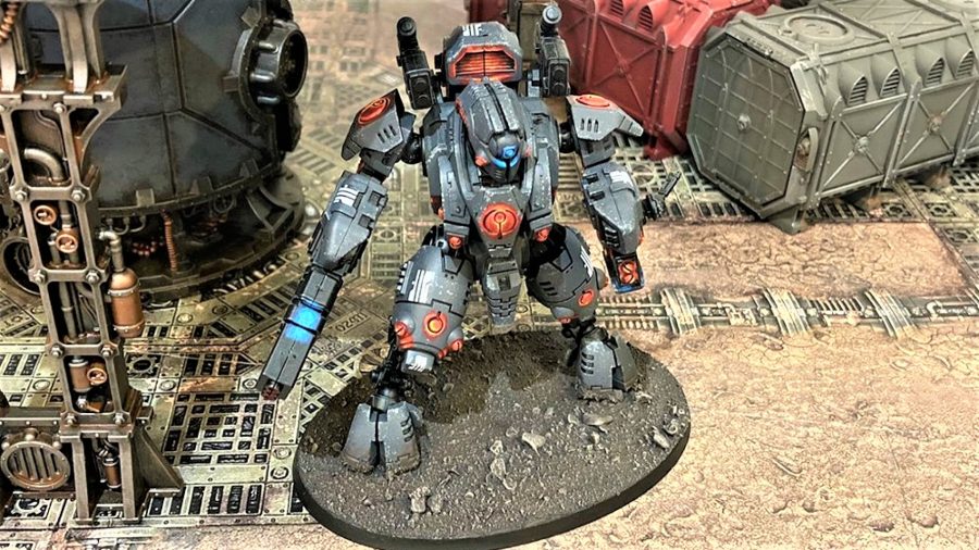 Warhammer 40K Xenos factions guide Tau empire photo showing a battlesuit model painted in dark colours