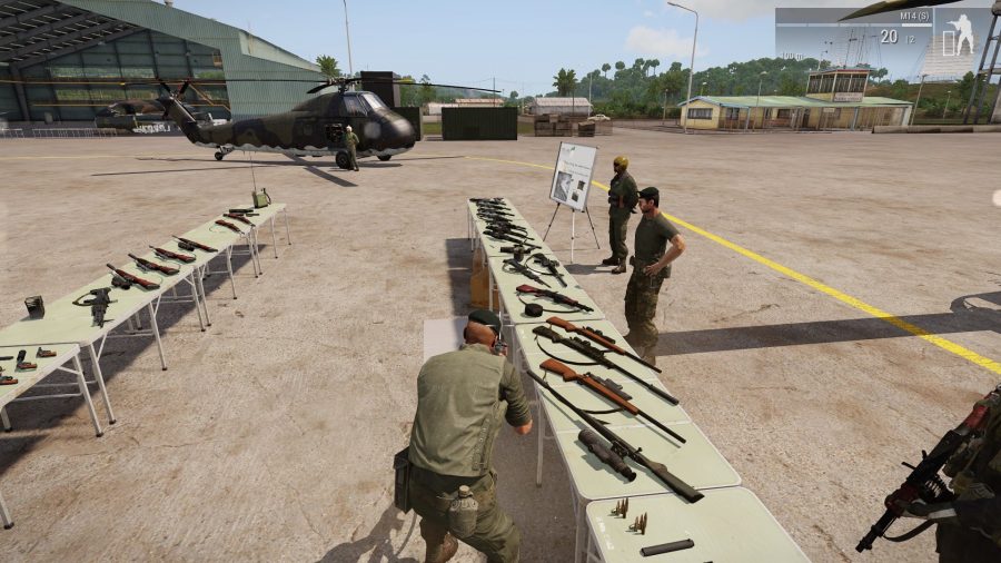 Screenshot from Arma 3 Creator DLC SOG Prairie Fire showing the armoury of weapons laid out on tables at base