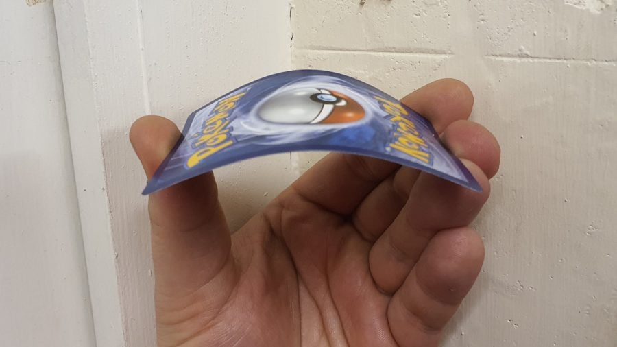 A photo of a hand bending a Pokemon card to test if it is a fake