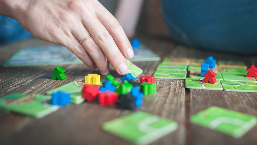 Best board game deals - photo of hand moving pieces in a game of Carcassonne board game