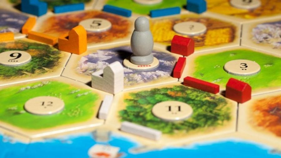 How to play Catan - Official Catan marketing photo showing the board hexes, pieces, and robber pawn close up