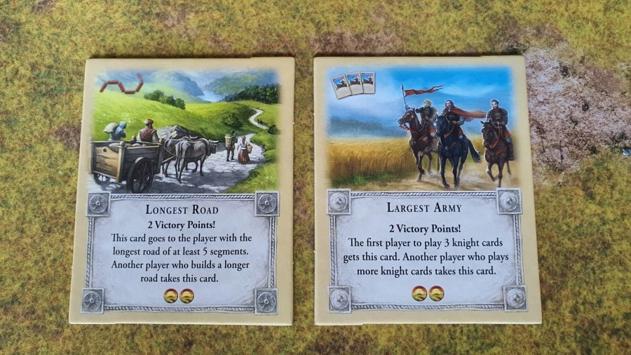 How to play Catan - Wargamer photo of Catan standard edition board game components, showing the victory point cards for Longest Road and Largest Army