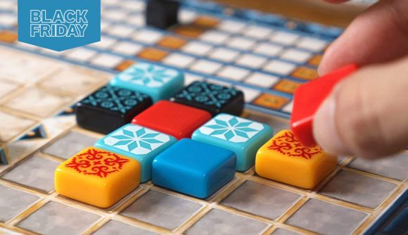 Someone placed a coloured tile on the board in a game of Azul. There is a Black Friday flag at the top left of the frame.