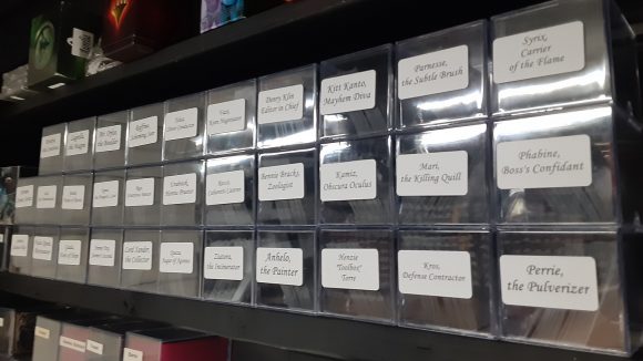 Magic the Gathering all commander decks: A row of storage containers labelled with the names of every legendary creature in the set Streets of New Capenna