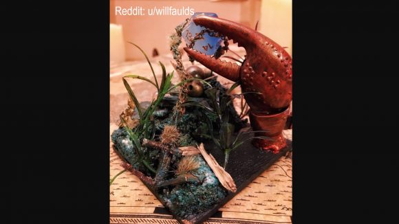 DnD dice DIY torture device - a custom miniature model of a lobster claw in a marshy terrain, holding a 20-sided die in its claw