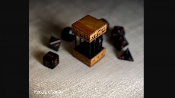 DnD dice DIY torture device - a handmade wooden jail with black bars, surrounded by black and red roleplaying dice