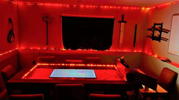 DnD ultimate gaming table setup lit by red LED lights around the walls of the room and on the inside of the table